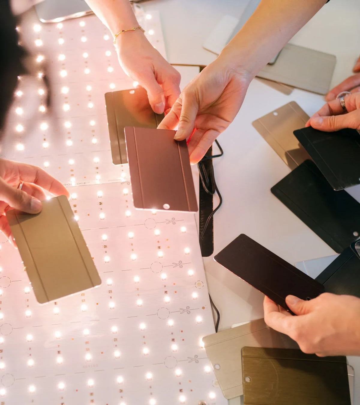 Designers comparing material samples over a lit LED panel